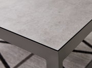 Nahaufnahme eines modernen Lounge-Tisches mit grauer Steinoptik-Oberfläche und stabilen Metallbeinen, perspektivisch von oben fotografiert.