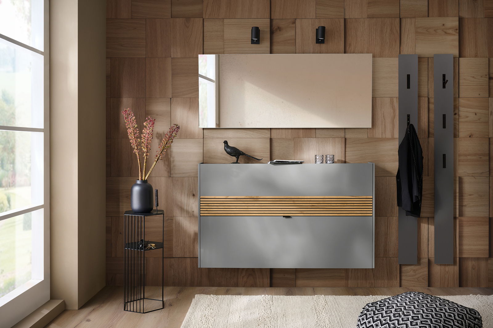 Voleo Garderoben-Set RIO Modernes Garderoben-Set in Graphit mit Holzdetails, bestehend aus einem Wandspiegel, einer Kommode und Kleiderhaken, aus der Perspektive eines hellen Raumes mit Holzwand.