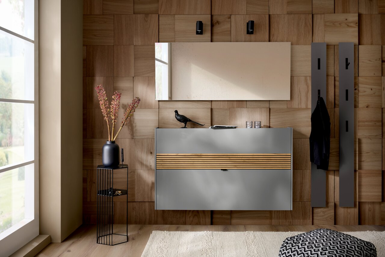 Modernes Garderoben-Set in Graphit mit Holzdetails, bestehend aus einem Wandspiegel, einer Kommode und Kleiderhaken, aus der Perspektive eines hellen Raumes mit Holzwand.