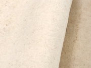 Nahaufnahme eines cremefarbenen Wollteppichs mit leichter Textur, seitliche Perspektive