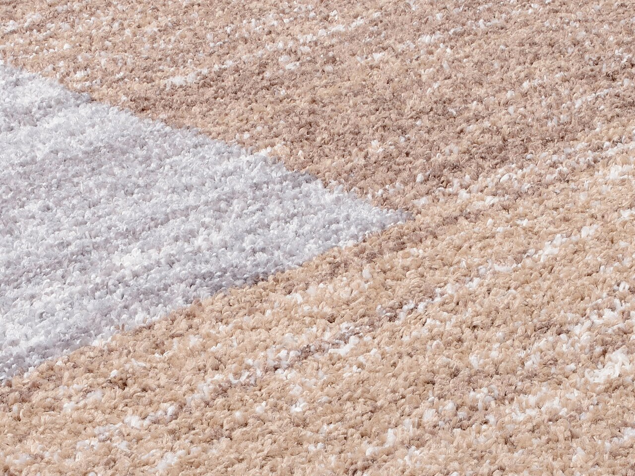 Nahaufnahme eines Frisé-Teppichs in Beige- und Grautönen, diagonale Perspektive.