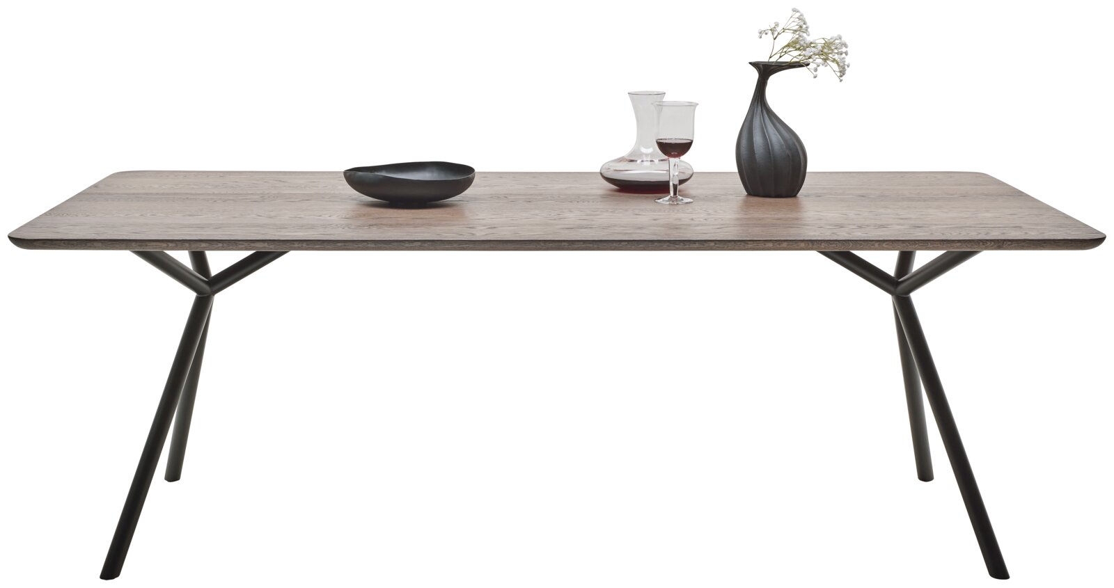 Moderner Esstisch mit Holzplatte und schwarzen Metallbeinen, seitliche Perspektive, dekoriert mit Vase, Weinglas und Schale.
