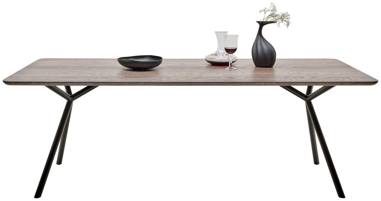 Moderner Esstisch mit Holzplatte und schwarzen Metallbeinen, seitliche Perspektive, dekoriert mit Vase, Weinglas und Schale.