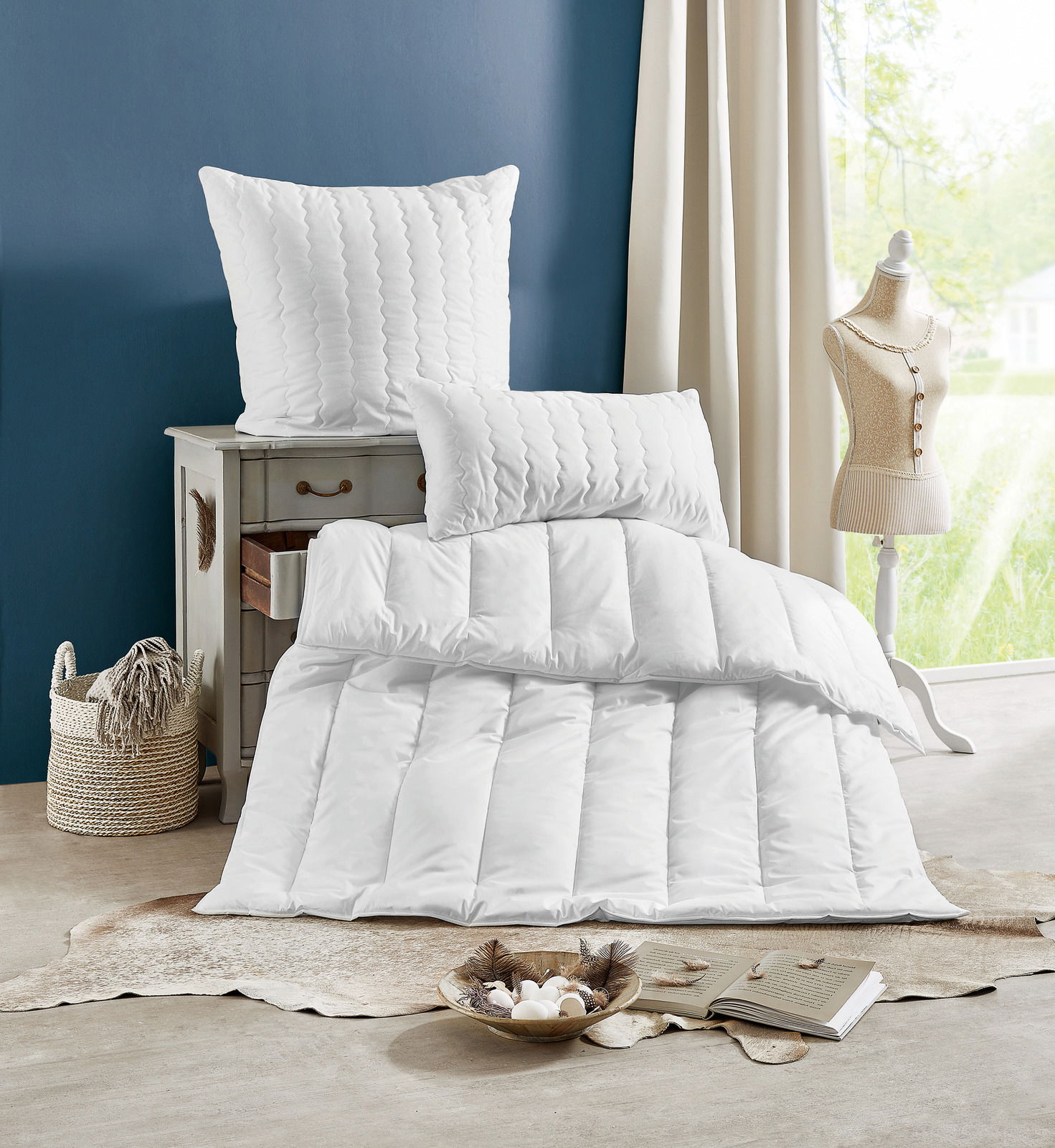 Centa Star Ganzjahres-Solo-Bett INSPIRATION in einem stilvollen Raum, mit einem Kissen auf einer Kommode und einer Bettdecke auf dem Boden, seitliche Perspektive