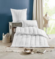 Centa Star Ganzjahres-Solo-Bett INSPIRATION in einem stilvollen Raum, mit einem Kissen auf einer Kommode und einer Bettdecke auf dem Boden, seitliche Perspektive