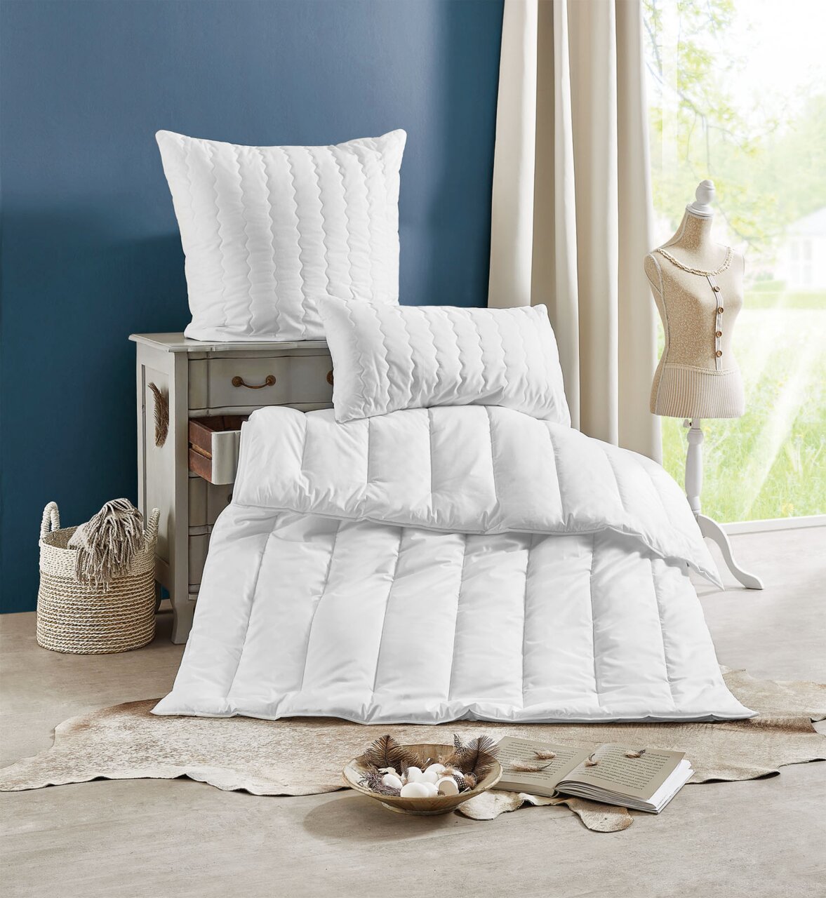 Centa Star Ganzjahres-Solo-Bett INSPIRATION in einem stilvollen Raum, mit einem Kissen auf einer Kommode und einer Bettdecke auf dem Boden, seitliche Perspektive