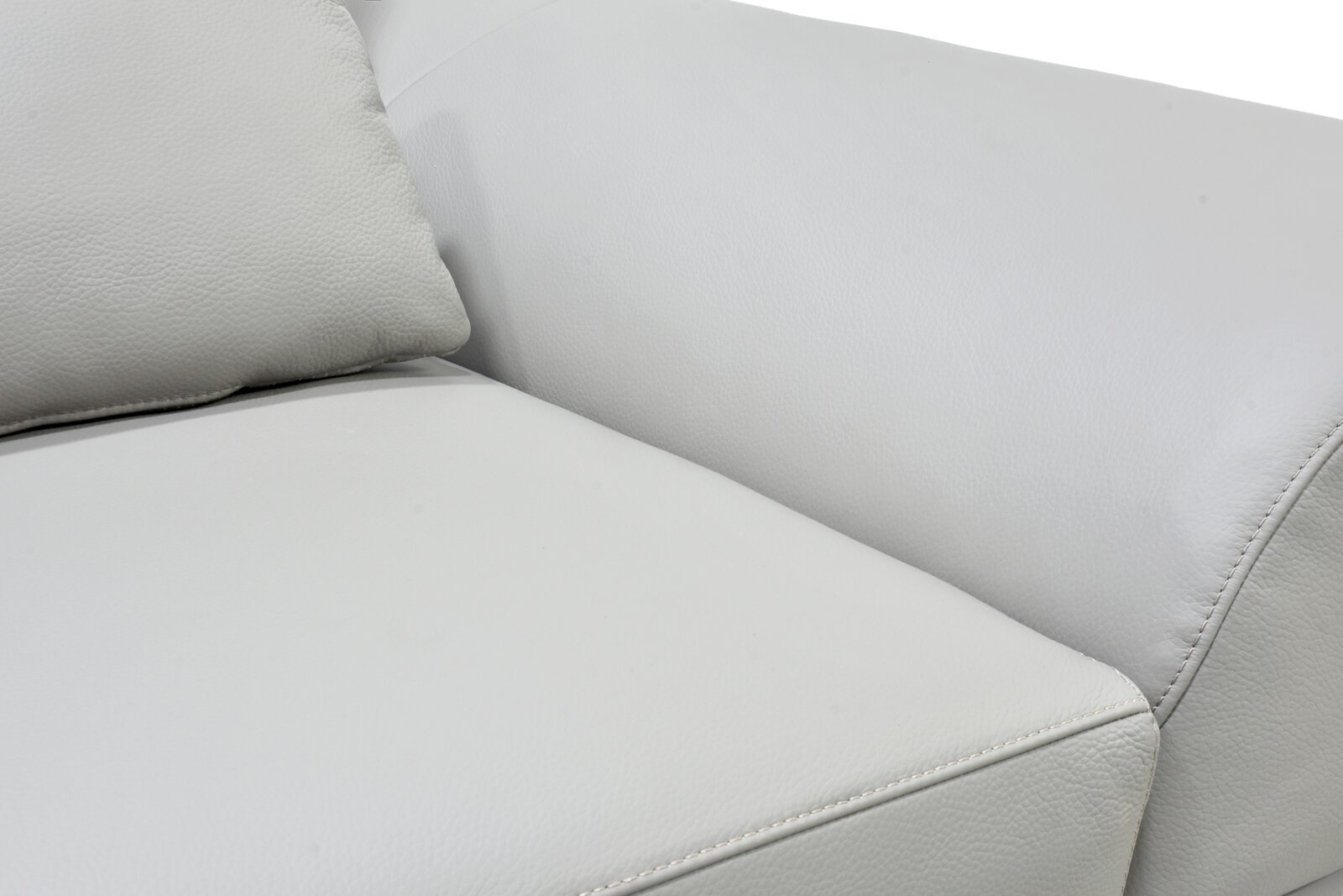 Detailaanzicht van een witte leren bank met fijn generfde bekleding, zachte kussens en verzorgde siernaden