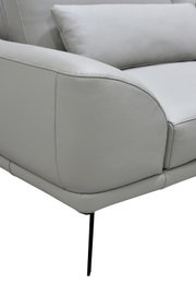 Detailaanzicht vanuit schuin vooraanzicht van een lichtgrijze fauteuil met zachte bekleding, afgeronde armleuning, sierstiksels, rugkussen en slanke zwarte metalen poot.
