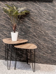 Zwei moderne Satztische mit hellen Holzplatten und schwarzen Hairpin-Beinen, im Vordergrund leicht schräg von vorn fotografiert; auf dem größeren Tisch steht eine grüne Zimmerpflanze im weißen Topf vor einer dunkel marmorierten Wand.