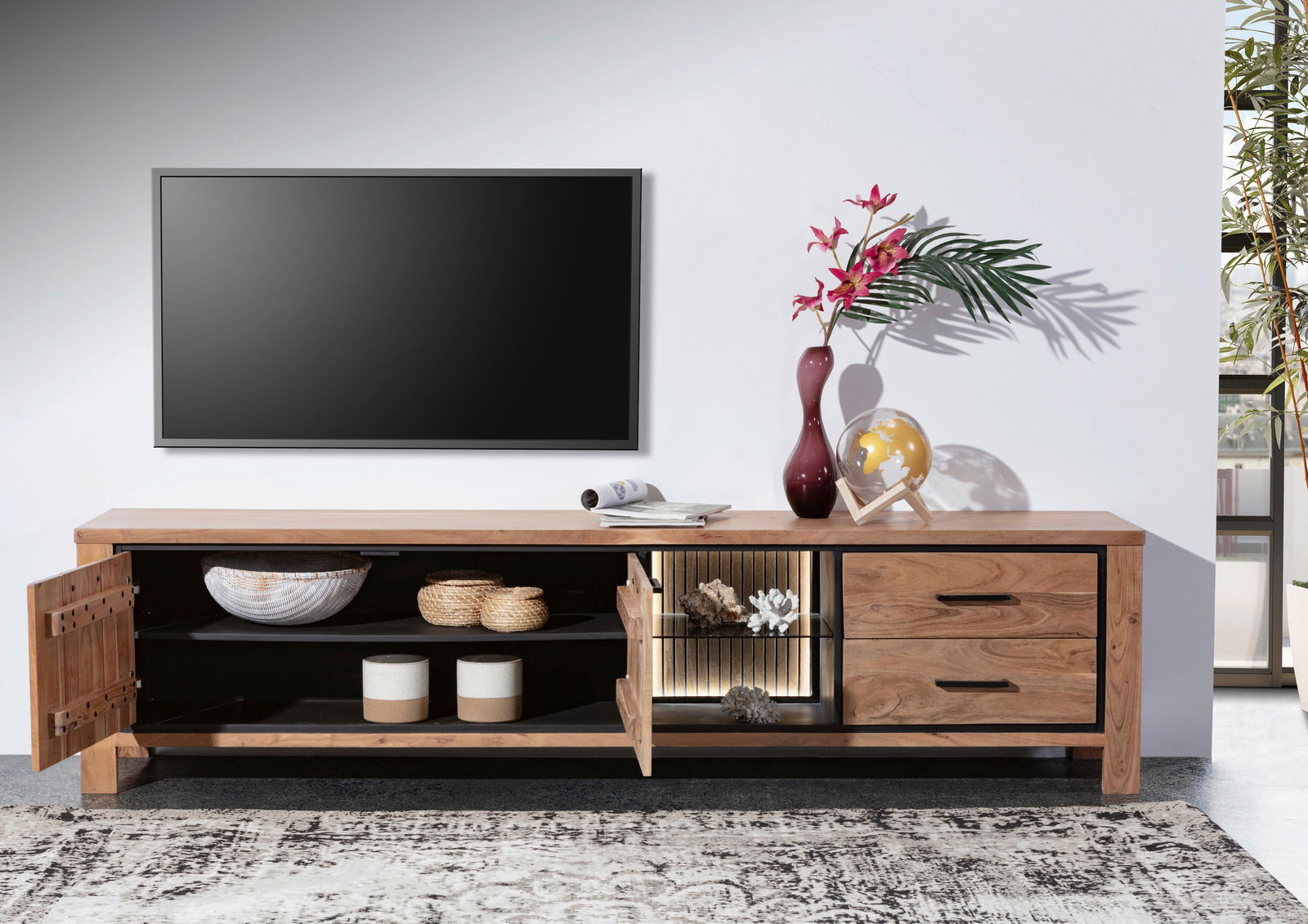 Frontale Ansicht eines Lowboards aus Holz mit offenen und geschlossenen Fächern, dekoriert mit Vasen und einem Globus, vor einer Wand mit einem Fernseher.