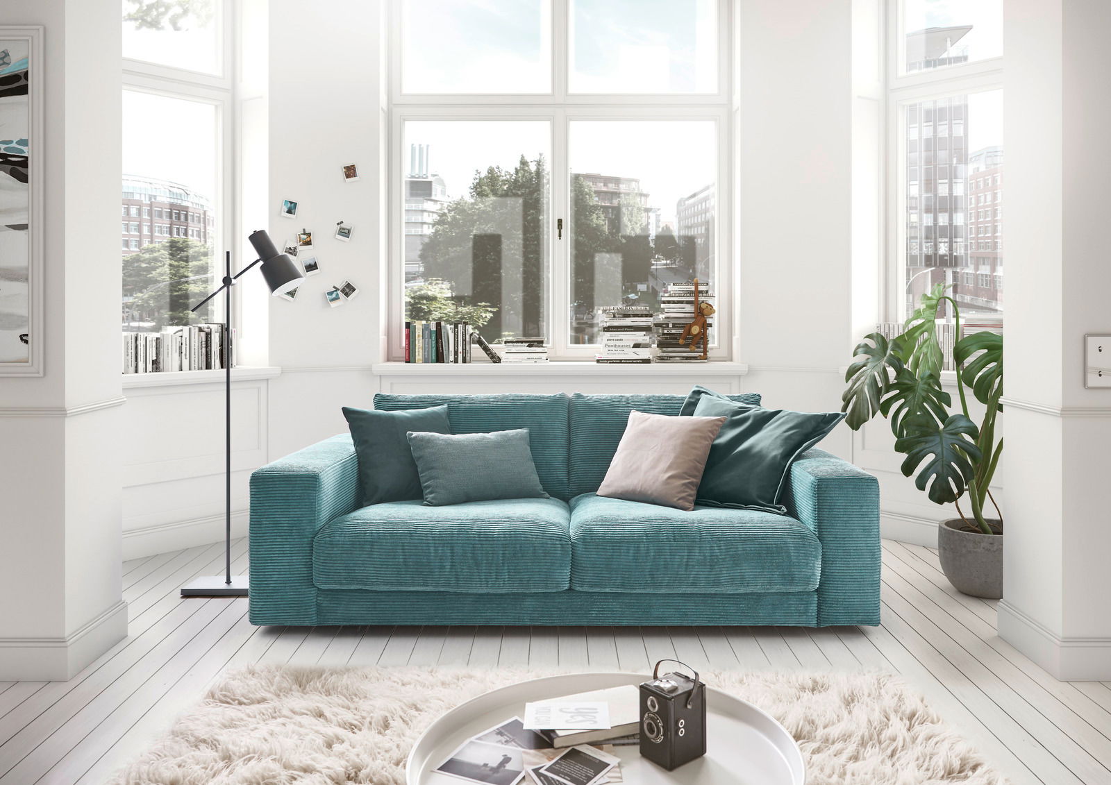 Lounge Handmade Sofa 2-Sitzer LH-SAMBIA Zweiersofa in einem modernen Wohnzimmer mit großen Fenstern, grünen Pflanzen und dekorativen Kissen, Frontalansicht.