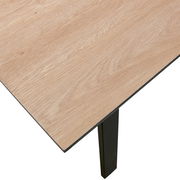 Nahaufnahme eines Esstisches mit heller Holzoberfläche und schwarzen Beinen, Perspektive von oben.