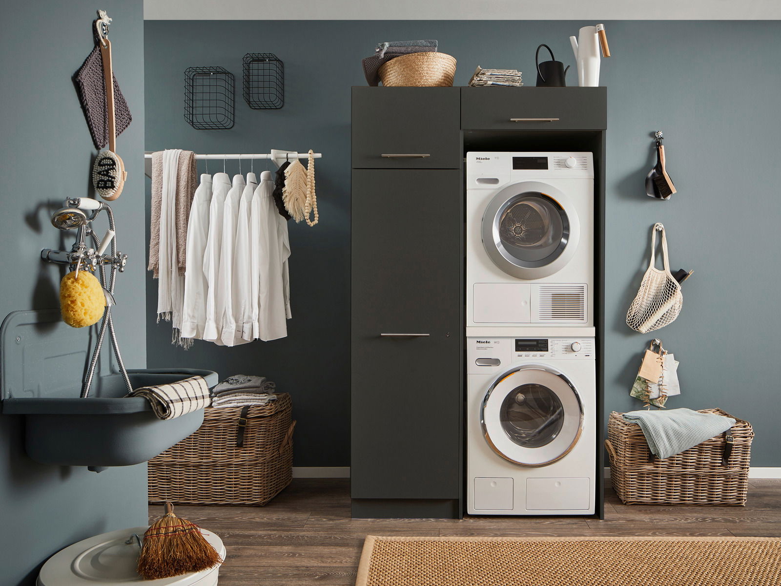 Hauswirtschaftsraum mit Waschmaschine und Trockner in einem modernen Schrank, umgeben von Wäschekörben und Hängeregalen, seitliche Perspektive.