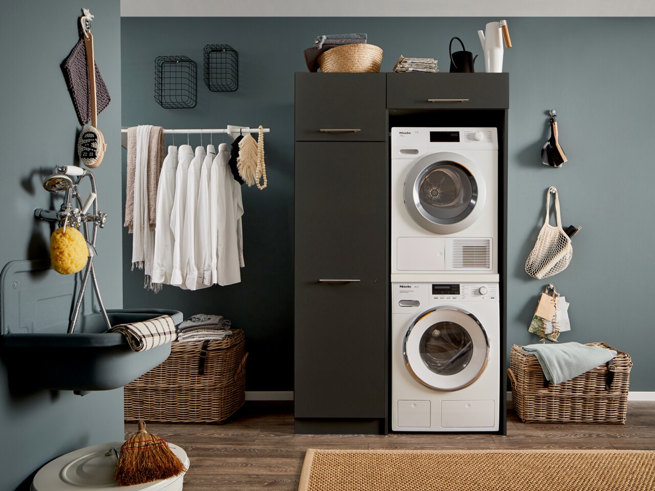 Hauswirtschaftsraum mit Waschmaschine und Trockner in einem modernen Schrank, umgeben von Wäschekörben und Hängeregalen, seitliche Perspektive.
