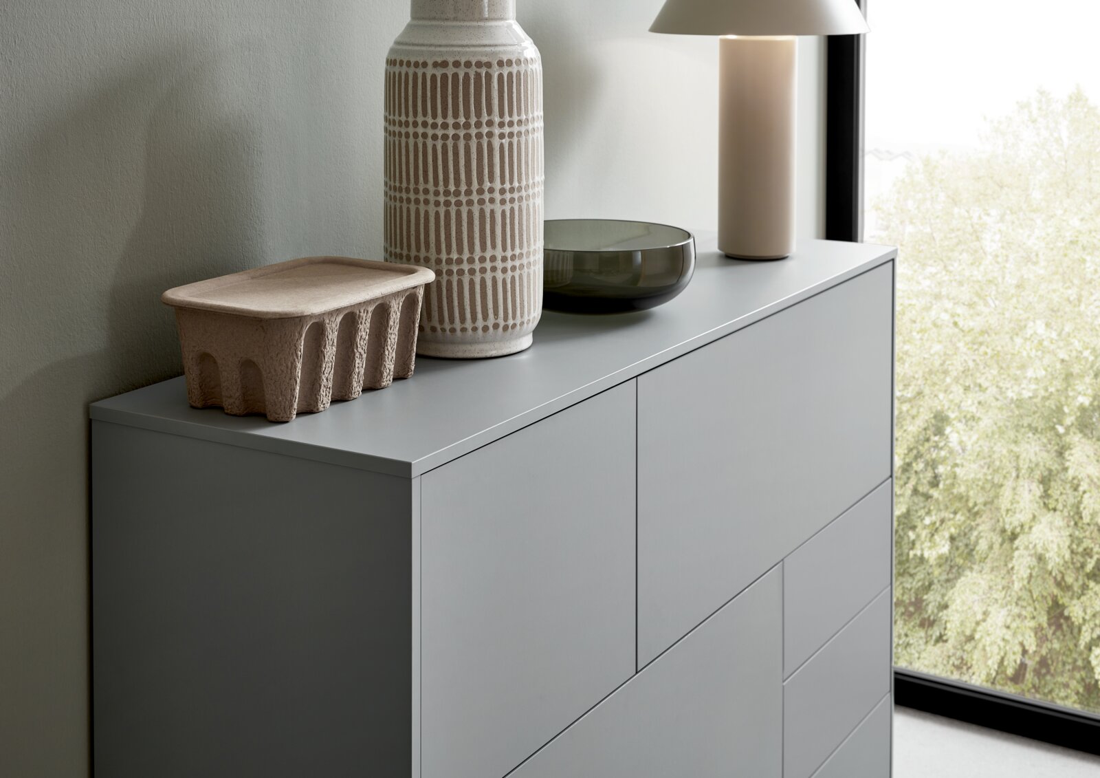 Modern grijs hoogkastje met decoratieve voorwerpen, gezien vanaf de zijkant