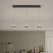 Moderne hanglamp met drie lampen, voorzien van drie ronde metalen kappen aan lange kabels en een rechthoekige plafondbeugel, gezien vanaf de voorkant vanuit een licht naar beneden gericht perspectief in de woonkamer