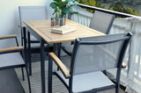 Moderner Gartentisch mit Holzplatte und Metallgestell, umgeben von Stapelsesseln auf einem Balkon mit Blick auf die Umgebung, seitliche Perspektive.