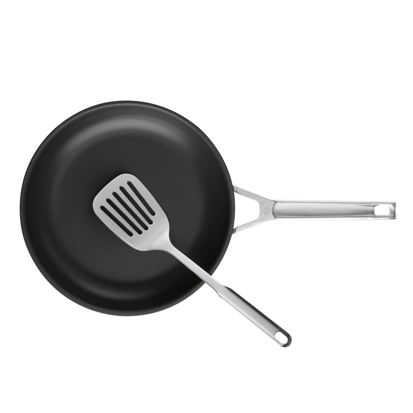 Schwarze Bratpfanne mit Edelstahlgriff und Edelstahl-Schlitzwender, Draufsicht von oben auf weißem Hintergrund
