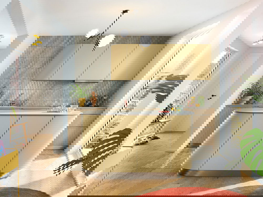 Moderne Designküche mit abgerundeter Insel in Senfgelb, grauer Fliesenrückwand und stilvoller Beleuchtung.