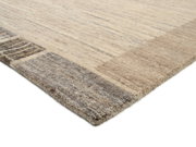 Nahaufnahme eines Wollteppichs mit dezenten Streifenmustern in Beige- und Grautönen, perspektivisch von der Seite aufgenommen.