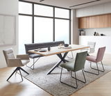 Moderner Esstisch aus Holz mit X-förmigem Metallgestell, umgeben von verschiedenen Stühlen in einem hellen, stilvollen Esszimmer. Perspektive von schräg vorne.