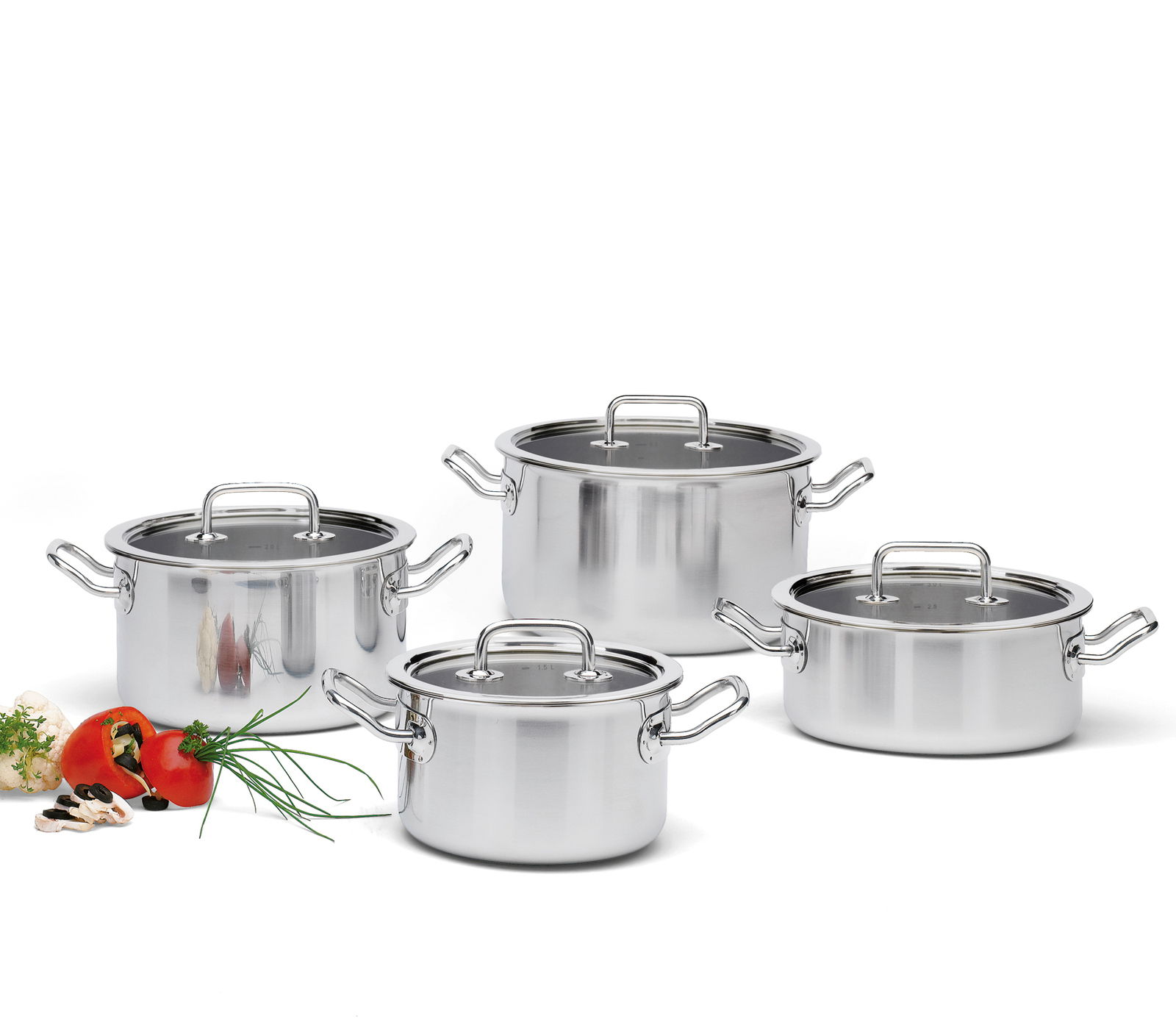 Vier-teiliges Topf-Set Brigade Basic aus Edelstahl, frontal fotografiert, mit Glasdeckeln und seitlichen Griffen, umgeben von frischen Zutaten wie Tomaten und Kräutern.