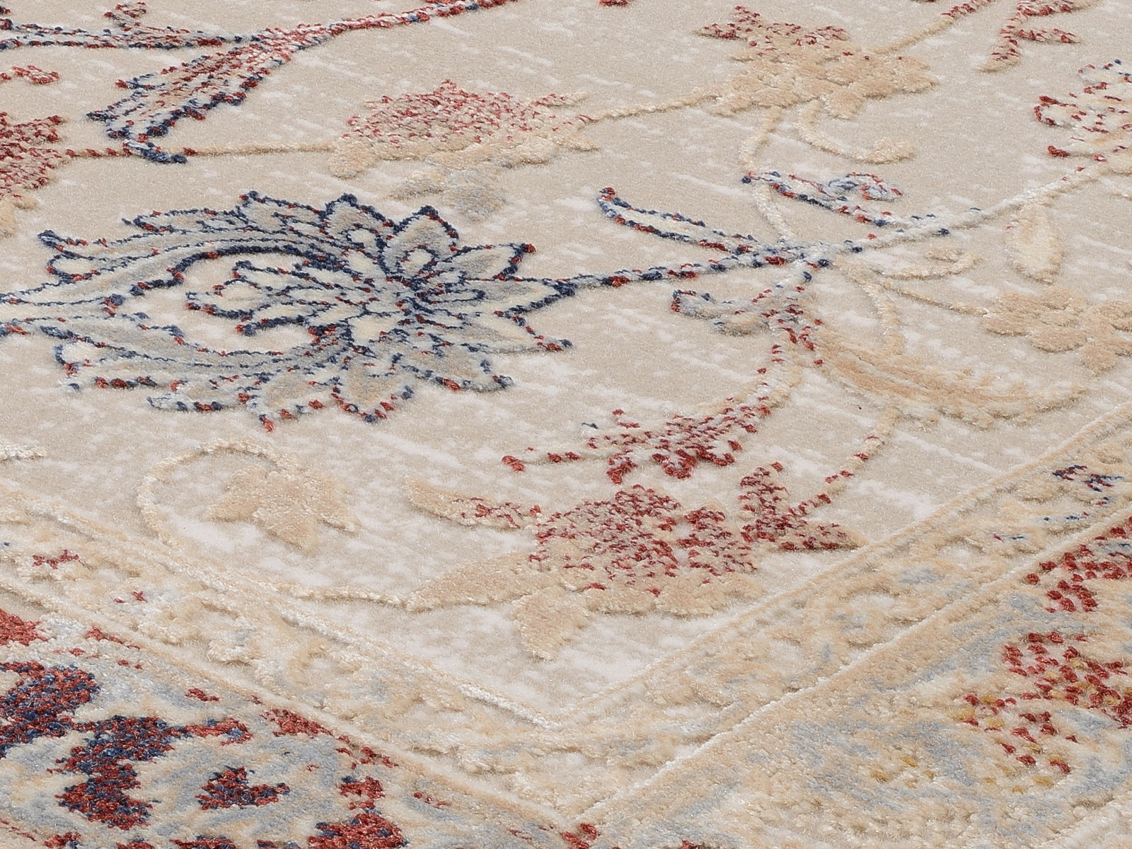 Nahaufnahme eines Orientteppichs mit floralen Mustern in Blau, Rot und Beige aus schräger Perspektive.