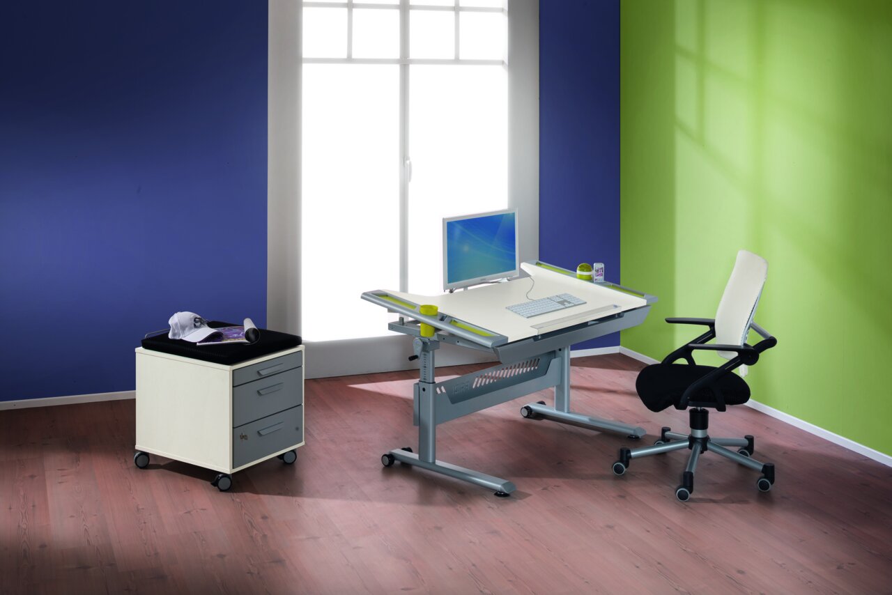 Paidi Bureau TABLO Moderner Schreibtisch mit verstellbarer Tischplatte, Computer und Bürostuhl in einem hellen Raum mit Holzfußboden, seitliche Perspektive.
