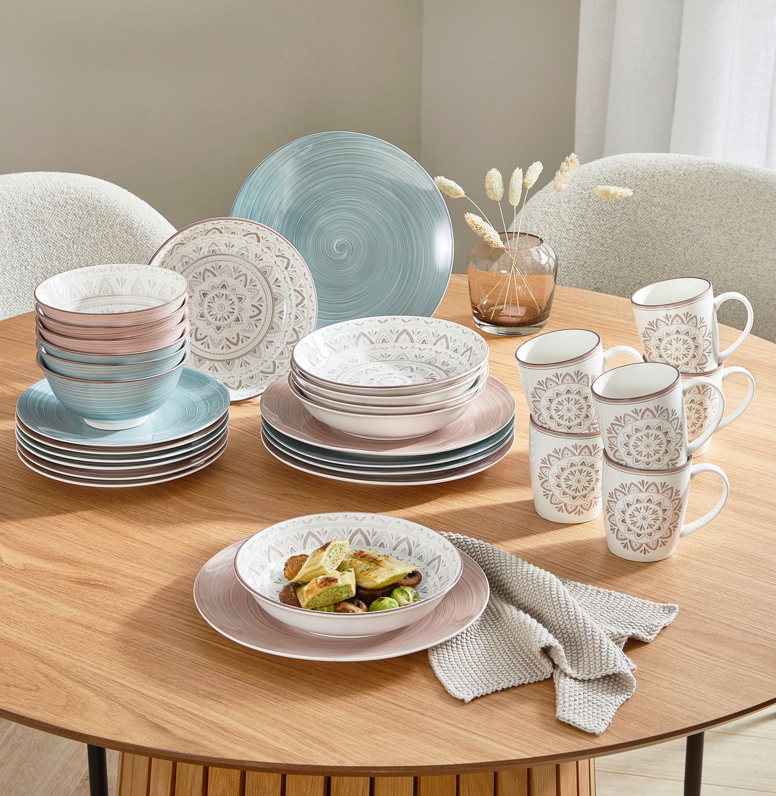 Porzellan-Set Valencia 30-teilig auf einem Holztisch, bestehend aus Tellern, Schalen und Tassen in Pastellfarben mit dekorativen Mustern, aus einer leicht erhöhten Perspektive fotografiert.