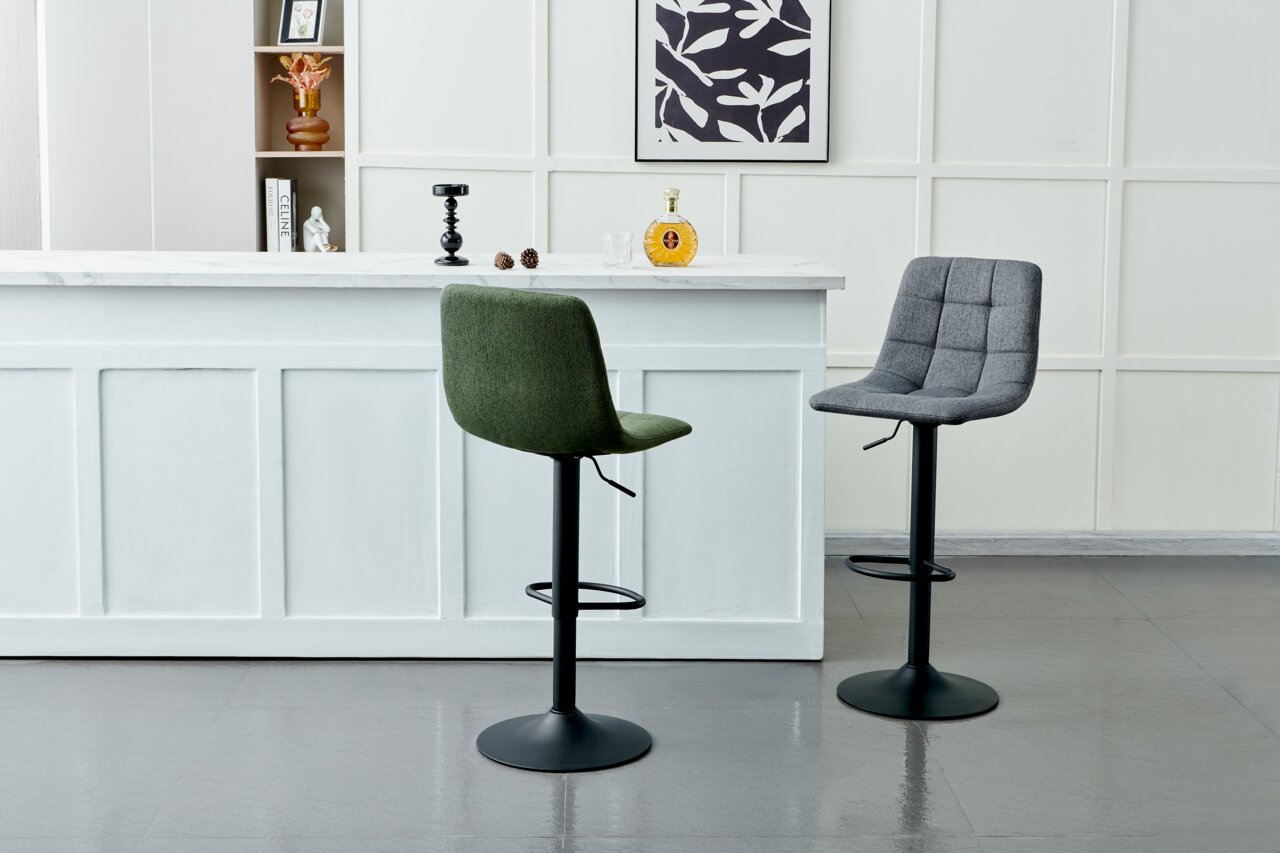 Zwei Barhocker mit gepolsterten Sitzen, einer in Grün und einer in Grau, vor einer weißen Theke in einer modernen Innenraumumgebung, seitliche Perspektive.