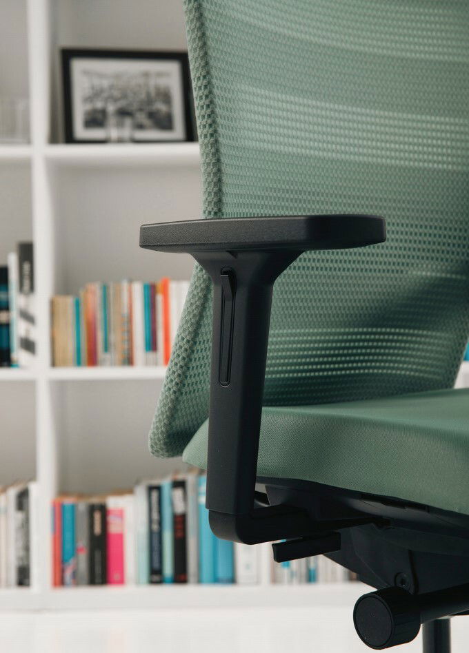 Seitenansicht eines grünen Bürostuhls mit Armlehne vor einem Bücherregal