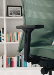 Seitenansicht eines grünen Bürostuhls mit Armlehne vor einem Bücherregal