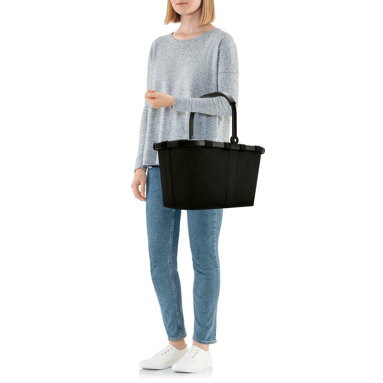 Eine Person hält einen schwarzen Carrybag mit einem stabilen Rahmen, seitliche Ansicht.