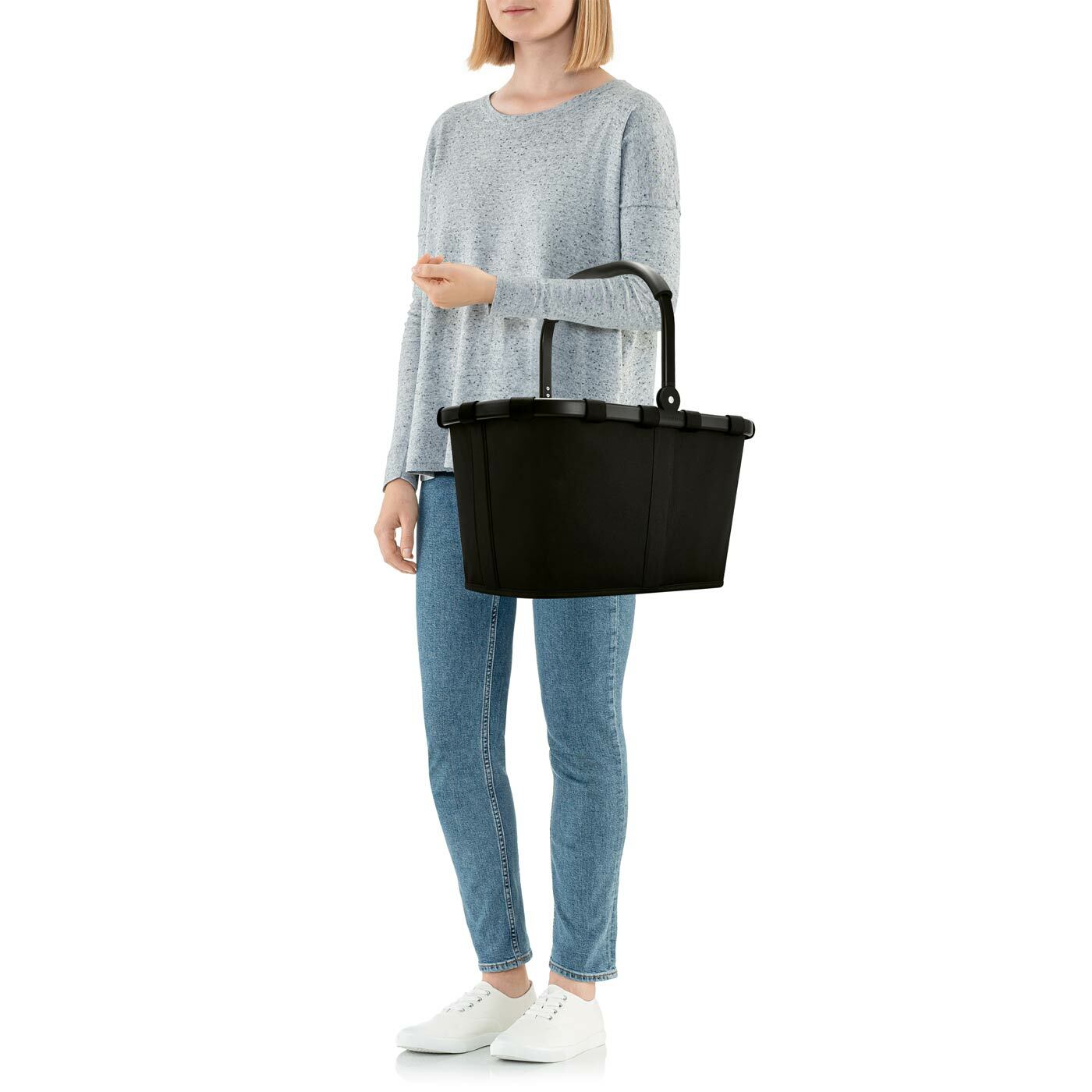 Eine Person hält einen schwarzen Carrybag mit einem stabilen Rahmen, seitliche Ansicht.