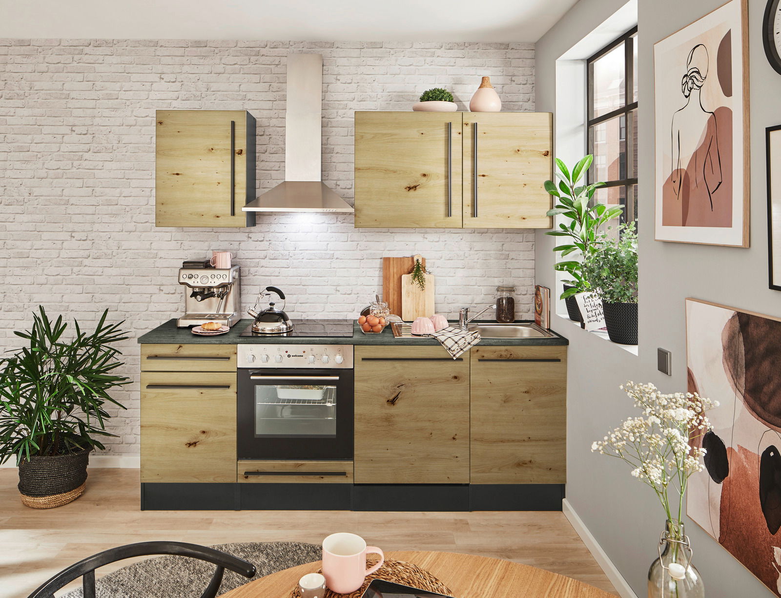 Moderner Küchenblock in Holzoptik ohne Elektrogeräte, frontal fotografiert, mit weißen Backsteinwänden und dekorativen Pflanzen.