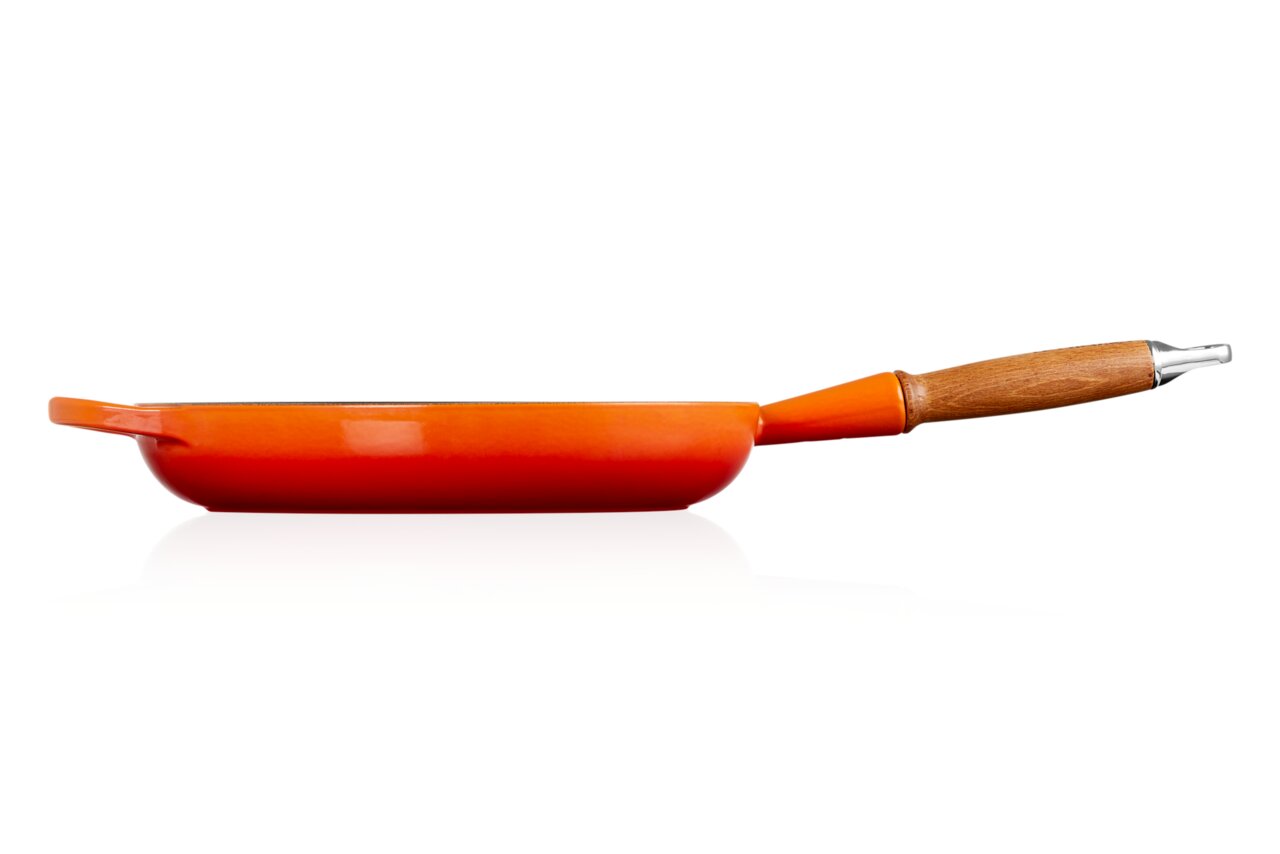 Zijaanzicht van een oranjerode koekenpan met houten handvat.