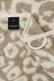Close-up van een beige handdoek met luipaardprint en een JOOP!-label.