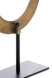 Close-up van een metalen ornament in de vorm van een ring op een zwarte standaard, gezien vanaf de zijkant.