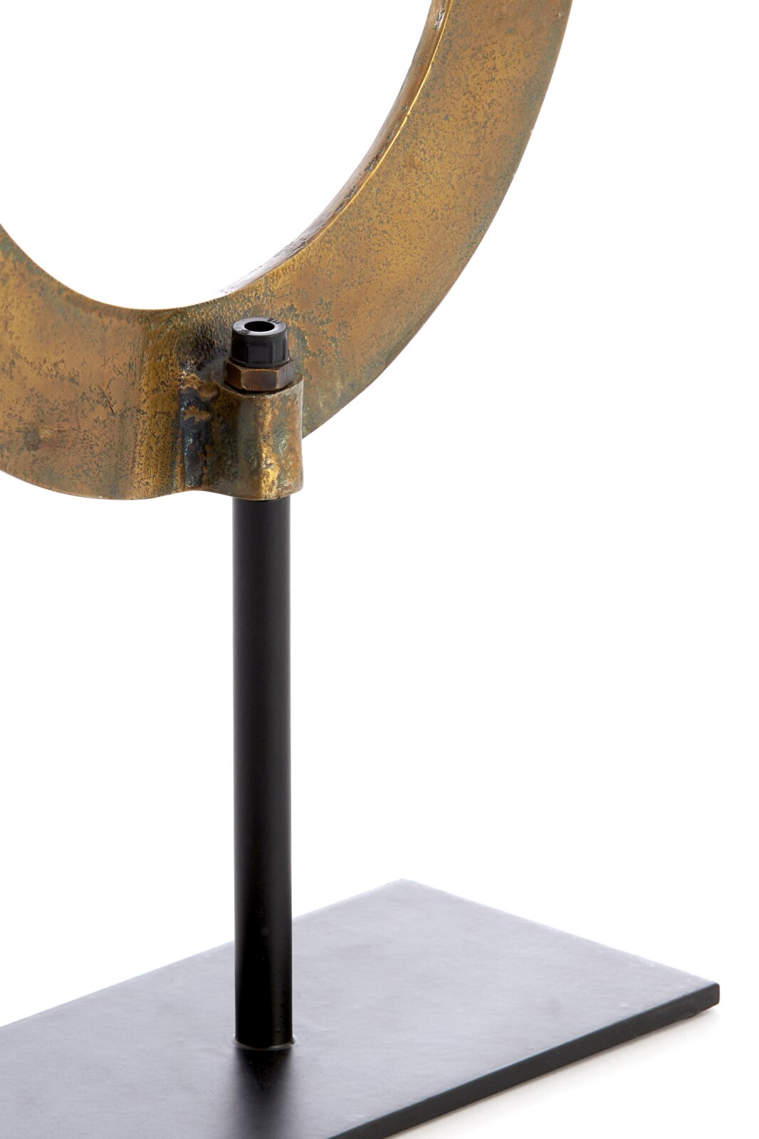 Close-up van een metalen ornament in de vorm van een ring op een zwarte standaard, gezien vanaf de zijkant.