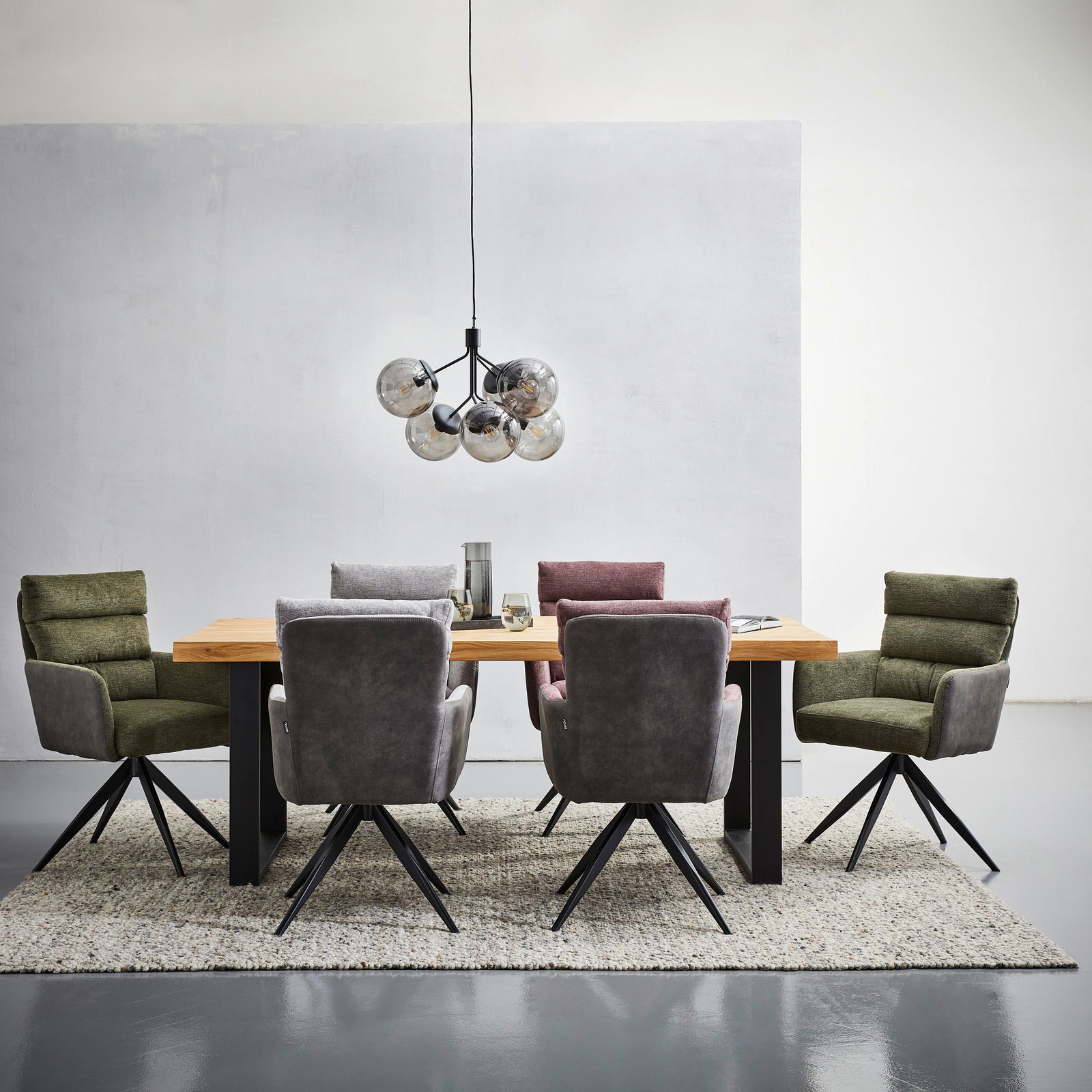 Moderner Esstisch 160x90 aus Holz mit schwarzen Beinen, umgeben von gepolsterten Stühlen in verschiedenen Farben, aus der Frontalperspektive fotografiert.