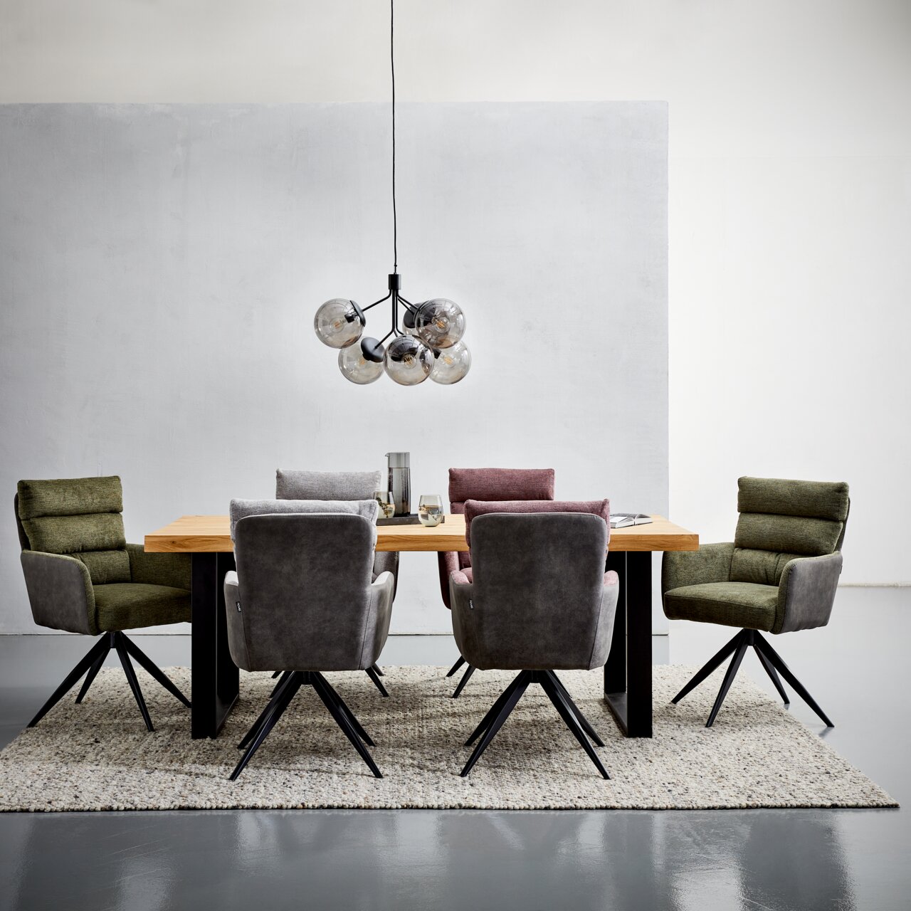 Moderner Esstisch 160x90 aus Holz mit schwarzen Beinen, umgeben von gepolsterten Stühlen in verschiedenen Farben, aus der Frontalperspektive fotografiert.