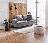 Graues Boxspring-Funktionssofa in modernem Wohnzimmer, seitliche Perspektive, mit einer Person, die darauf sitzt und ein Buch liest.