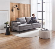 Graues Boxspring-Funktionssofa in modernem Wohnzimmer, seitliche Perspektive, mit einer Person, die darauf sitzt und ein Buch liest.