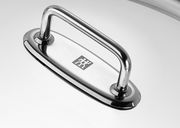 Nahaufnahme eines glänzenden Edelstahlgriffs auf einem Wok-Deckel, von oben betrachtet.