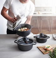 Dreiteiliges Topfset in moderner Küche, Perspektive von oben, mit dampfendem Topf und zubereitetem Lachs.