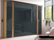 Moderner 6-türiger Drehtürenschrank mit Holzrahmen und dunklen Glastüren, seitliche Perspektive im Schlafzimmer.
