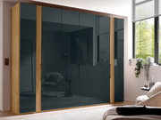 Moderner 6-türiger Drehtürenschrank mit Holzrahmen und dunklen Glastüren, seitliche Perspektive im Schlafzimmer.