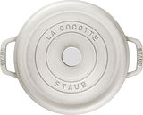 Runde, cremefarbene Bräter Cocotte von oben mit der Aufschrift 'La Cocotte Staub' auf dem Deckel.