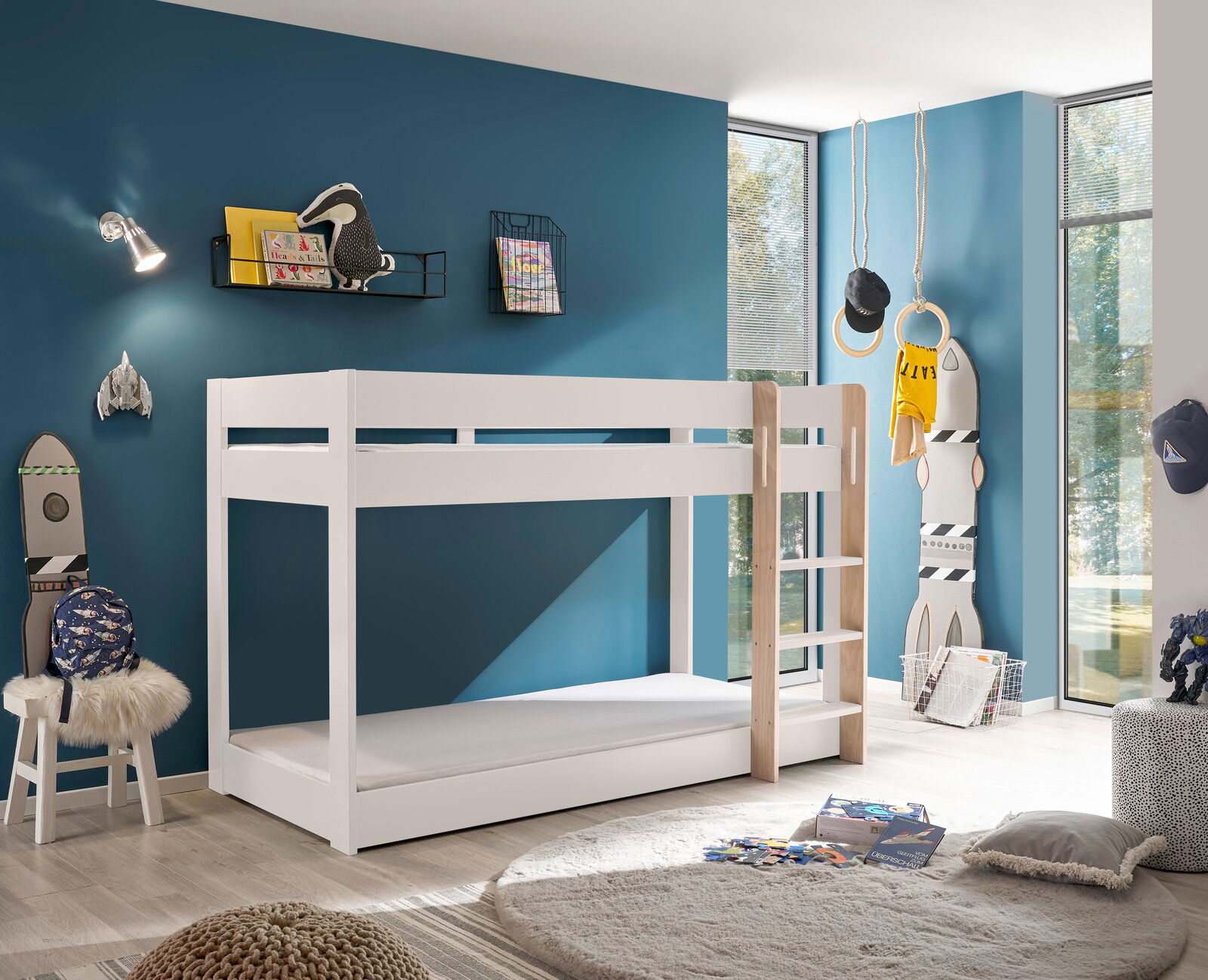 Weißes Etagenbett in einem modernen Kinderzimmer mit blauer Wand, von der Seite betrachtet.