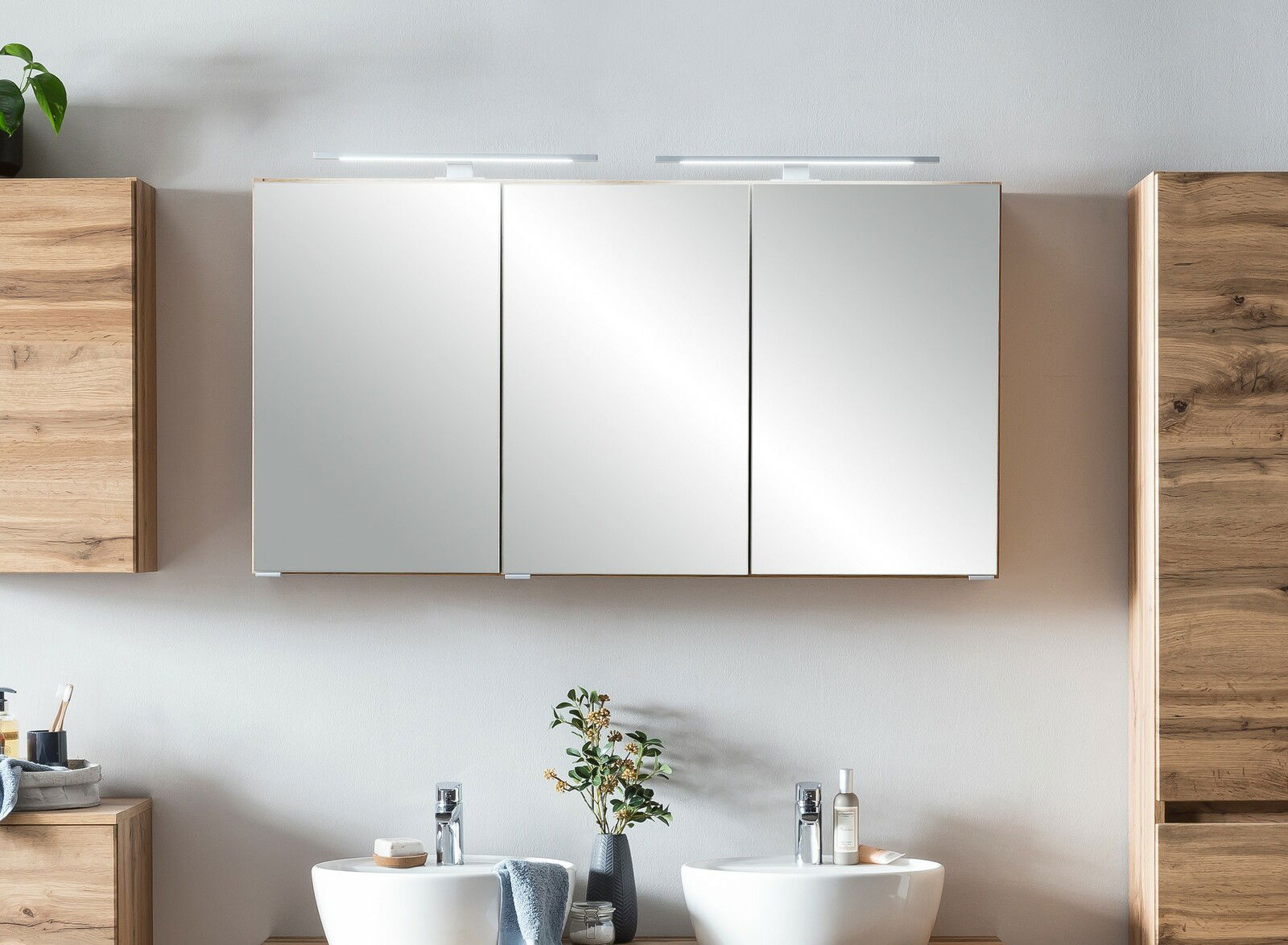 Moderner Spiegelschrank mit drei Türen und integrierter Beleuchtung, frontal betrachtet.